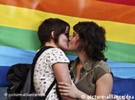 Дві лесбійки цілуються на фоні веселкового прапора у Ліссабоні