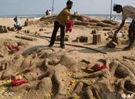 Flores e esculturas na areia da praia de Chennai, Índia, em homenagem às vítimas
