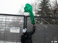 جوانی در حال افکندن پرچم سبز به داخل کنسولگری جمهوری اسلامی