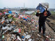In this photo taken Monday, Feb. 1, 2010, a farmer walks past a garbage dump site near a village in Hefei, in central China's Anhui province. (AP Photo) ** CHINA OUT **