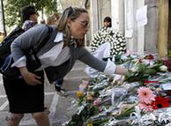 A woman leaves flowers, outside the central Athens bank building where three workers died in a fire 