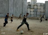 Palestinian boys play soccer next to the concrete blocks that separate the southern Gaza Strip 