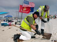 Workers hired by BP pick up tar balls as they work along Pensacola Beach, Florida