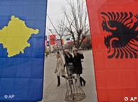 Kosovo women walk in the main square decorated with flags for the anniversary of Kosovo's independence