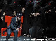 Actors in rat costumes surround a seated actor in 
