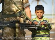 Criança segura metralhadora de soldado inglês, no Iraque