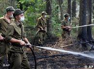 Soldiers spray water from hoses in a forest