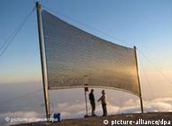 Fog collecting net in Chile with two people standing underneath it.
