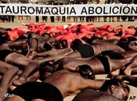 Activists hold a banner reading ''Abolish bullfighting'', as people cover their bodies with red and black during a protest