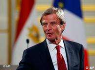Bernard Kouchner in front of a French flag