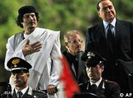 Libyan leader Moammar Gadhafi, standing at left, and Italian Premier Silvio Berlusconi, right, review the honor guard ahead of a horse show