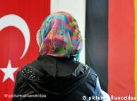 A woman with a headscarf stands in front of German and Turkish  flags