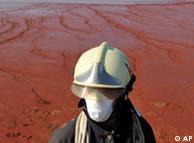 A Hungarian firefighter stands guard at the red sludge