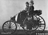 Carl Benz (right) in his patented vehicle