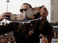 An anti-government protester tears a picture of Egyptian President Hosni Mubarak