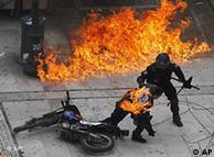 A policeman tries to help a colleague hit by a firebomb