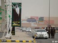 Saudi policemen forming a check point stand near a picture of King Abdullah 