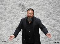Chinese artist Ai Weiwei poses with some seeds from his art installation 'Sunflower Seeds' in London, Monday, Oct. 11, 2010. The specially commissioned art piece takes the form of a field of sunflower seeds inside the Turbine Hall at Tate Modern gallery, made of over 100 million handmade unique porcelain replicas of sunflower seeds, made by Chinese Artist Ai Weiwei, and will run until May 2, 2011. (AP Photo/Lennart Preiss)