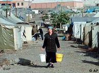 A woman carries buckets of water at a camp for Chechen refugees