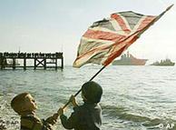 Young boys wave a Union flag as the British Aircraft Carrier Ark Royal is pulled by a tug as it leaves Portsmouth 